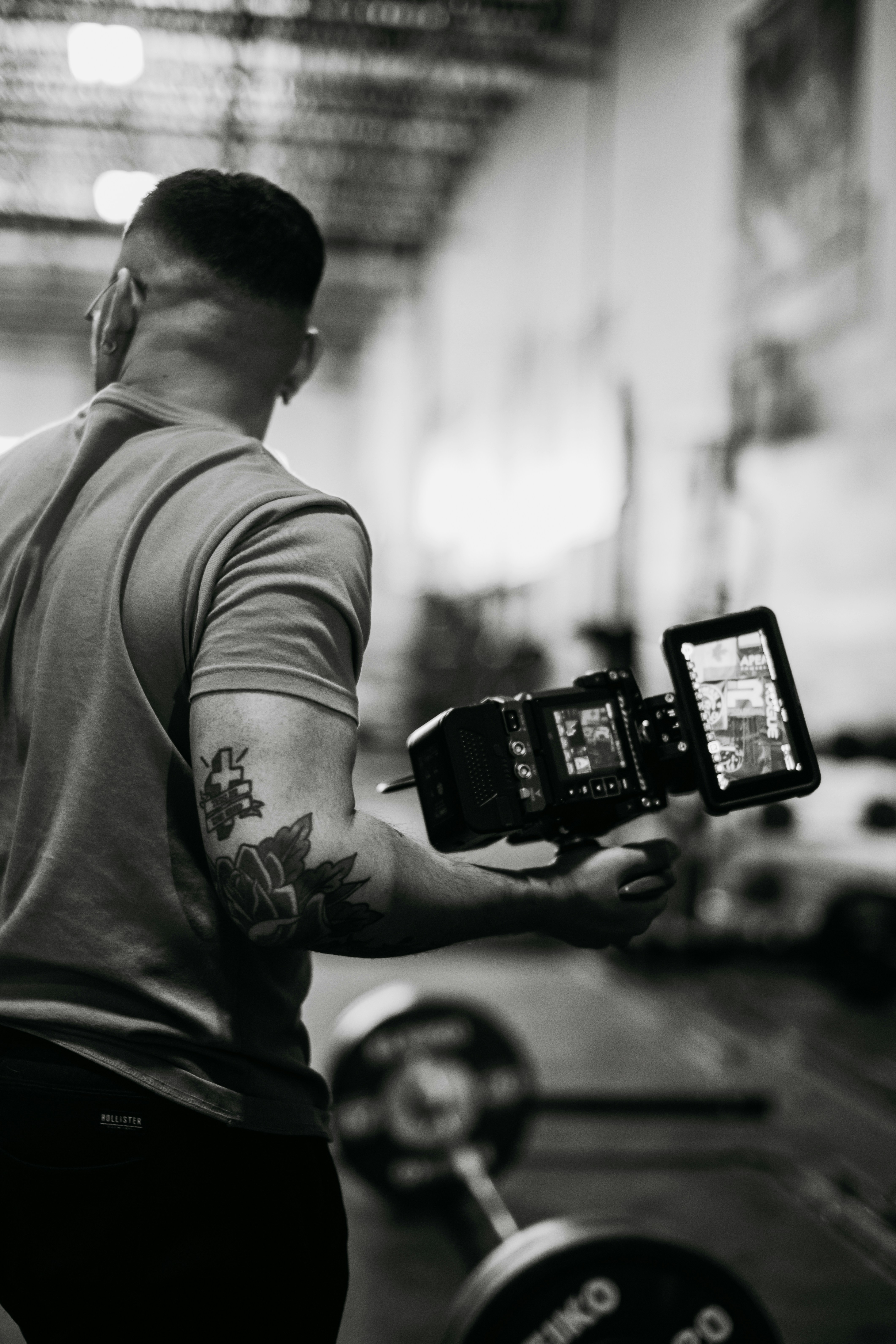 A fitness creator filming themselves with a phone on a tripod in a gym.
